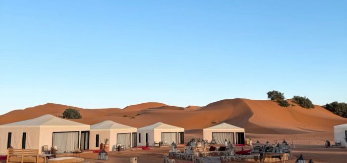 Sahara desert camp with tents illuminated at dusk
