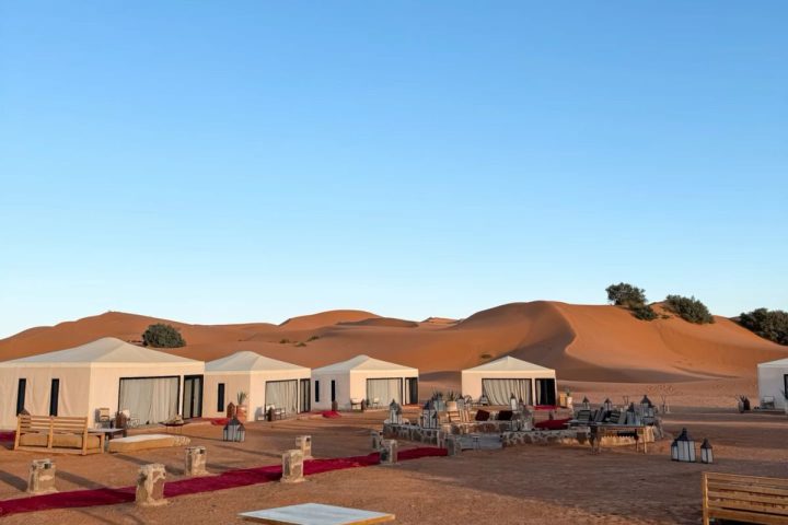 Sahara desert camp with tents illuminated at dusk